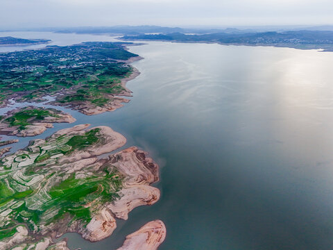 Aerial view of the stark contrast between the lush green landscapes and the calm expanse of the water, Chakswari, Azad Kashmir, Pakistan.