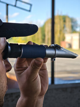 Quality control in winemaking: Winemaker using a refractometer to measure sugar levels in Mendoza.