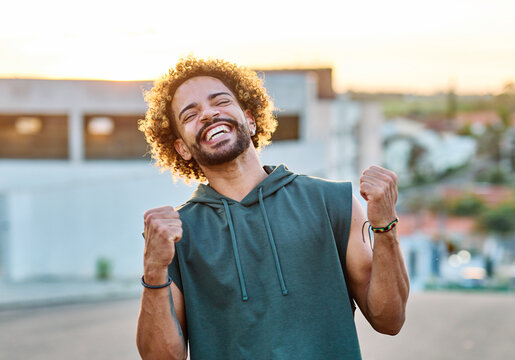 Portrait of a smiling young man jogging exercising and having fun and  celebrating victory outdoors