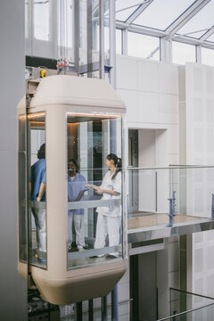Distant view of medical team standing in elevator at hospital building