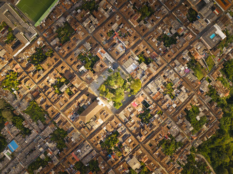 Aerial view of terracotta rooftops cascading in geometric harmony, punctuated by verdant plazas and sun-kissed streets, Salamina, Caldas, Colombia.