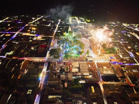 Aerial view of a dazzling spectacle of fireworks exploding above the central plaza, illuminating the colonial architecture with vibrant colors, Salamina, Caldas, Colombia.