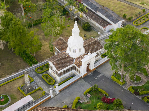 Aerial view of the Immaculate Conception Archdiocesan Sanctuary, its white facade gleaming against the terracotta roofs and manicured gardens, a serene landmark., Salamina, Caldas, Colombia.