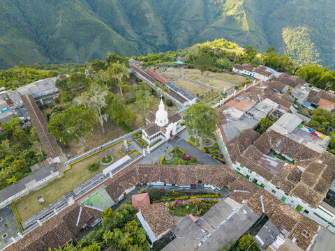Aerial view of the Immaculate Conception Archdiocesan Sanctuary standing tall with its white facade against a backdrop of lush green hills, Salamina, Caldas, Colombia.