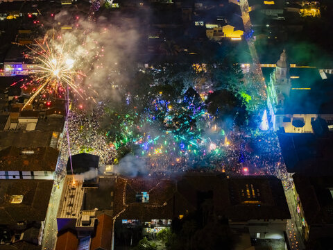 Aerial view of a vibrant explosion of light and sound over the town square, where fireworks illuminate the historic church and the lively crowd below, Salamina, Caldas, Colombia.