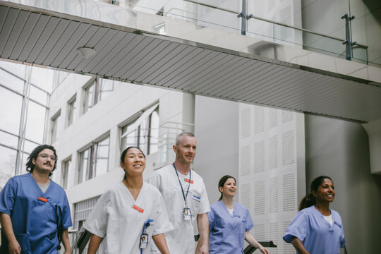 Confident male and female medical professionals walking in hospital lobby