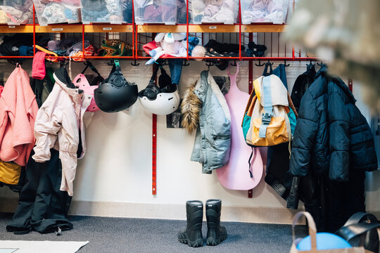 Colorful winter coats and jackets along with backpacks hanging on hooks at preschool