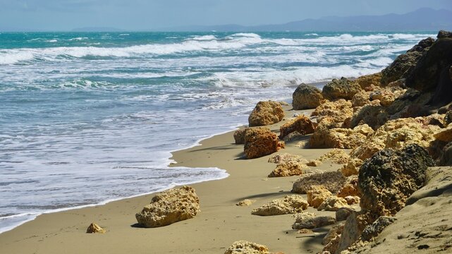 Deserted Caribbean beach with golden sand, breaking waves and limestone boulders, Dominican Republic