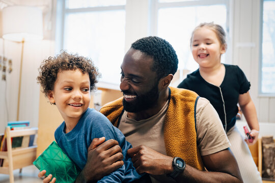 Happy male teacher spending leisure time with elementary students in classroom