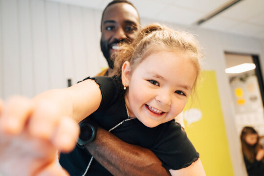 Portrait of cheerful girl sharing joyful moment with teacher during break time at preschool