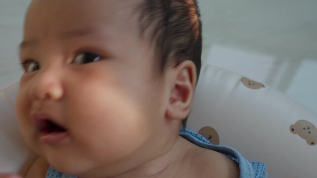 Close-up portrait of cute Asian baby looking at camera, showing innocence, soft skin, and natural expression. Concept of newborn care, family love, parenting, and healthy child development.