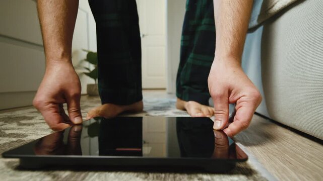 Macro close-up: man's bare feet step onto a weighing scale during morning routine at home. Focus on health consciousness, weight management and wellness lifestyle 4K.