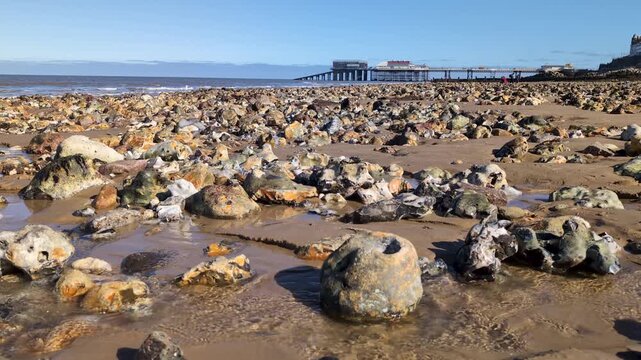 Scenic view of Cromer Pier with sandy beach in the foreground along the North Sea coast in Norfolk, showcasing a classic British seaside landscape and coastal architecture on a clear day
