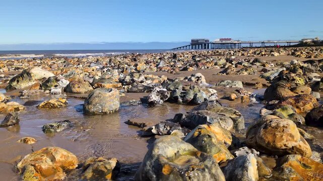 Scenic view of Cromer Pier with sandy beach in the foreground along the North Sea coast in Norfolk, showcasing a classic British seaside landscape and coastal architecture on a clear day
