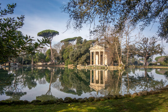 The Temple of Asclepius reflected in the calm lake of Villa Borghese park. A picturesque and romantic landmark for travel and tourism in Rome, Italy.