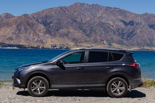 February 4, 2019, Queenstown, New Zealand - Dark grey Toyota RAV4 parked by a lake with mountains in the background