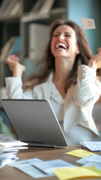 Woman with laptop laughing while frantically working, stressed out office environment