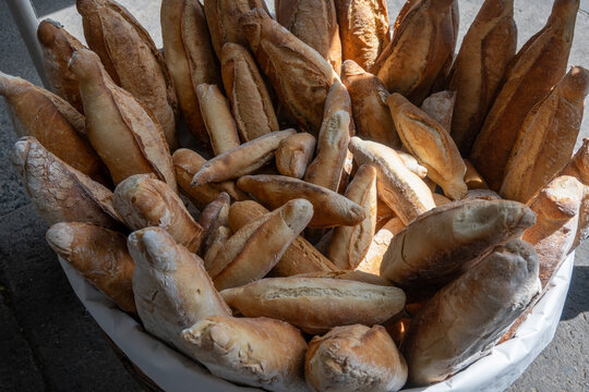 A large basket filled with traditional Virote bread loaves, fresh from the oven, ready for sale in Guadalajara city center. Close up of golden brown crusts.