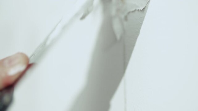 Handyman filling holes on white wall with putty knife, wall preparation process, high quality 10 bit 4K.