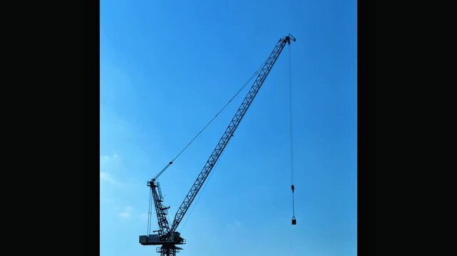 Industrial tower crane at construction site against clear blue sky urban development background