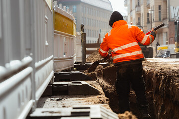 Fototapeta premium Kanalarbeiter schippt Sand in den Schacht
