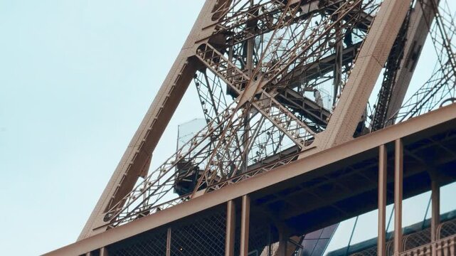 Eiffel Tower Iron Structure with Silhouetted People Walking on Stairs Against Blue Sky in Paris