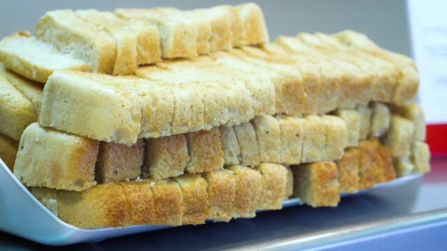 Stack of Toasted Bread Slices on a Tray in a Industrial Canteen. Rusks Served at a Workers Cafeteria Buffet