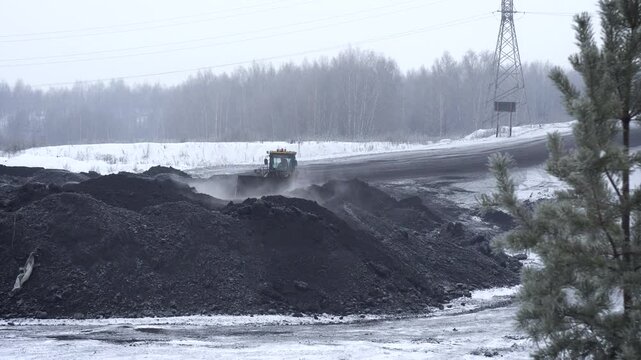 Wheel Loader Moving Coal Mounds at an Outdoor Mining Site in Winter. Heavy Industrial Machinery Working at a Snowy Open Pit Mine