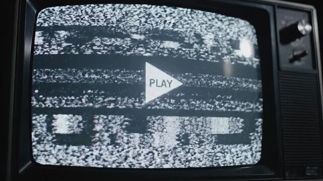 This shows an old television screen with a static error screen and a play button in the center. The screen is filled with white noise and distorted images, indicating a technical difficulty or signal