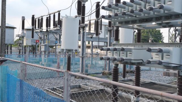 Electrical substation power grid high voltage engineer inspection with safety helmet, reflective vest and tablet, transformer switchgear utility yard