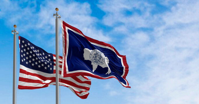 Wyoming state flag and the american flag waving together on a clear day