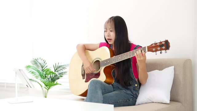 Teens girl learns to play the guitar, music lesson with online teacher, distance learning to play the guitar.