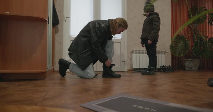 Man and child put on footwear winter shoes. 4K 10-bit