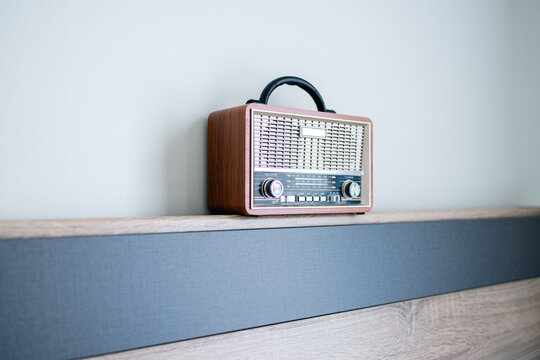 Vintage Retro Radio on Wooden Shelf with Minimalist Background,A classic vintage-style portable radio with a wooden finish and analog tuning dial, placed on a modern wooden shelf against a clean