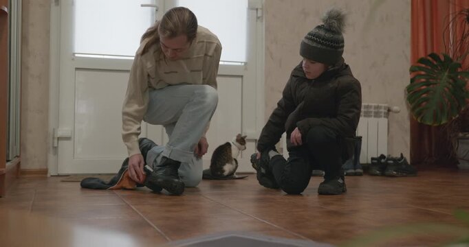 Man and child put on footwear winter shoes. 4K 10-bit