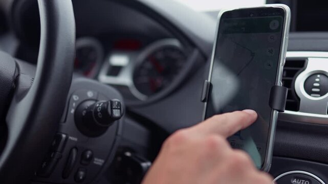 A taxi driver plots a route map on a smartphone by swiping a finger across the smartphone screen, A driver in motion looks at a car using the phone as a navigator map for a trip