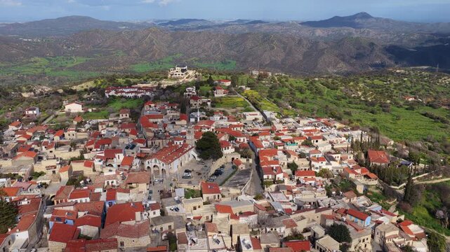 Aerial drone view of a traditional Cypriot village featuring a historic church with bell tower and red tiled roofs. Pano Lefkara, Cyprus