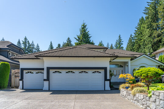 Garage door in luxury house with trees and nice landscape in Summer in Vancouver, Canada, North America. Day time on August 2025.