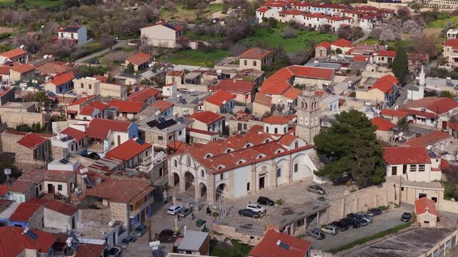 Aerial drone view of a traditional Cypriot village featuring a historic church with bell tower and red tiled roofs. Pano Lefkara, Cyprus