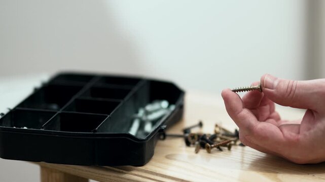 Man's hand picking up fastener from toolbox compartment, furniture assembly process, professional 10-bit 4K UHD.