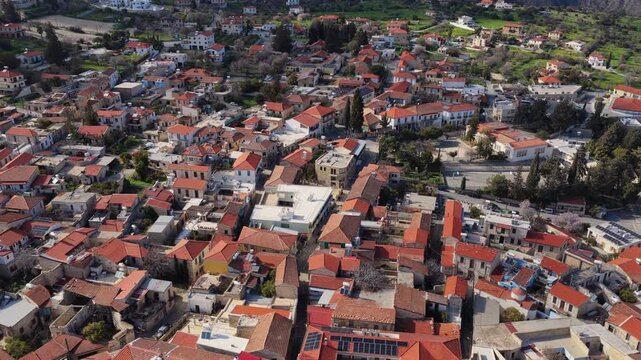 Aerial drone view of a traditional Cypriot village featuring a historic church with bell tower and red tiled roofs. Pano Lefkara, Cyprus