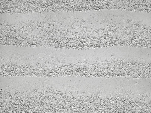 Background of texture rammed white earth wall with uneven, rough, horizontal grain pattern. Environmentally friendly building material with a minimalist aesthetic for modern architecture or interiors.