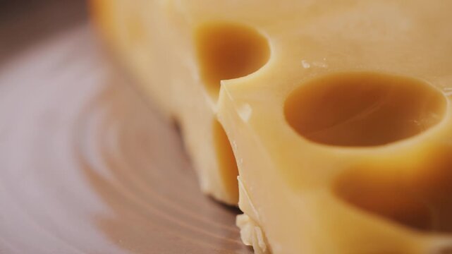 Bright yellow Emmental cheese or Maasdam cheese with large holes close up.