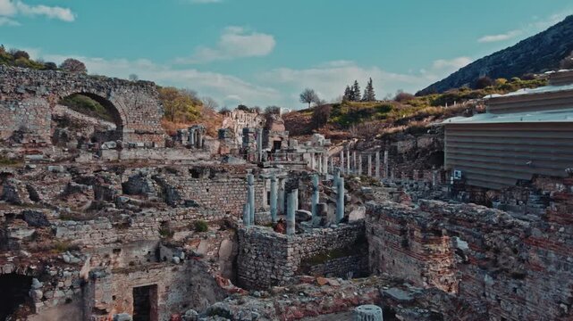 Panoramic view of ancient ruins in Ephesus, Izmir, Turkey. Historic stone walls, arches, columns and layered archaeological remains under blue sky reveal the timeless atmosphere of antiquity.