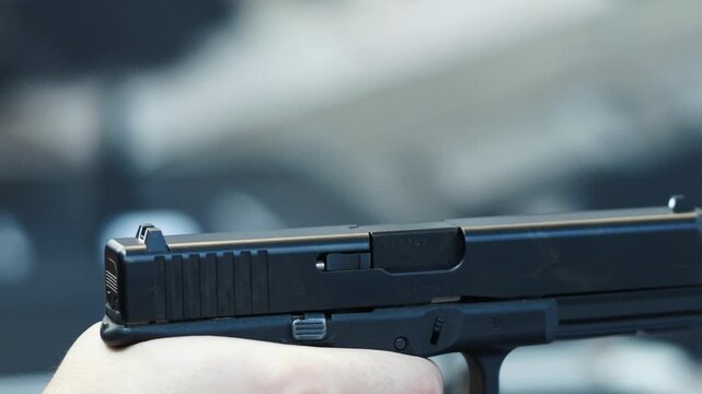 close-up of a person holding a handgun.

Key details:
The firearm appears to be a semi-automatic pistol, held firmly in one hand.
The person&rsquo;s finger is inside or near the trigger guard, suggesting re