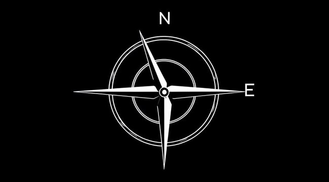Close up of a compass needle pointing north on a black background.