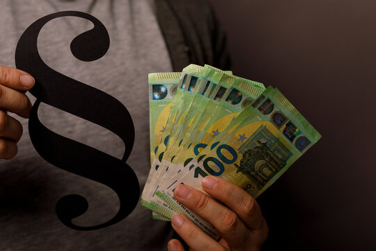 Image of a person holding Euro banknotes next to a paragraph symbol, representing legal finance conc
