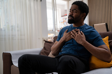 Fototapeta premium Black man feeling sudden chest pain in the living room