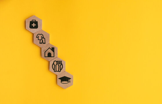 wooden cube with icons of food, Clothing, housing, medical bag, four basic human needs concepts. The Four Basic Material Needs of the Human Being.