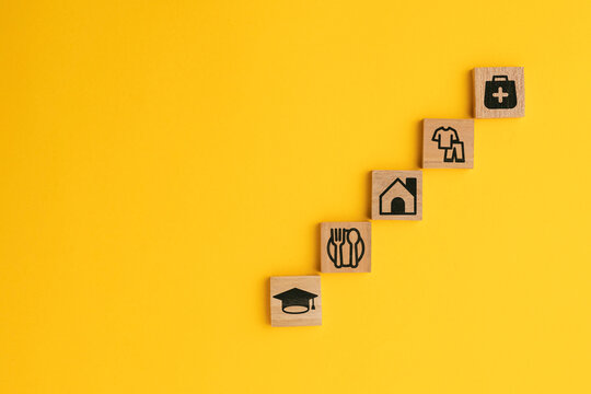 wooden cube with icons of food, Clothing, housing, medical bag, four basic human needs concepts. The Four Basic Material Needs of the Human Being.